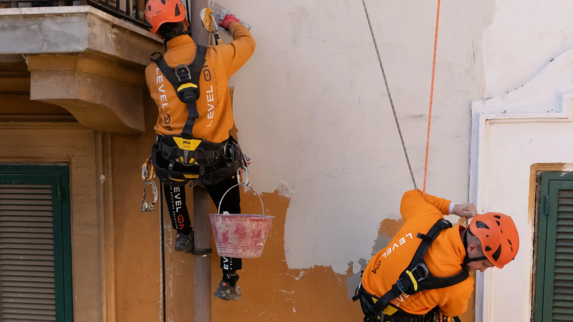 Dos técnicos de Level On reparan el revestimiento exterior de una fachada residencial mediante acceso por cuerda.