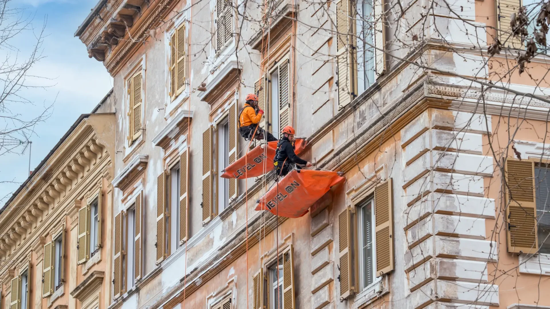Dos técnicos de Level On realizan trabajos verticales sobre las molduras de una fachada en Barcelona mediante acceso por cuerda.