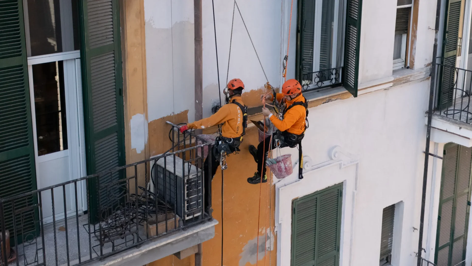Dos técnicos de Level On realizan trabajos verticales de reparación y acabado en una fachada de Barcelona mediante acceso por cuerda.