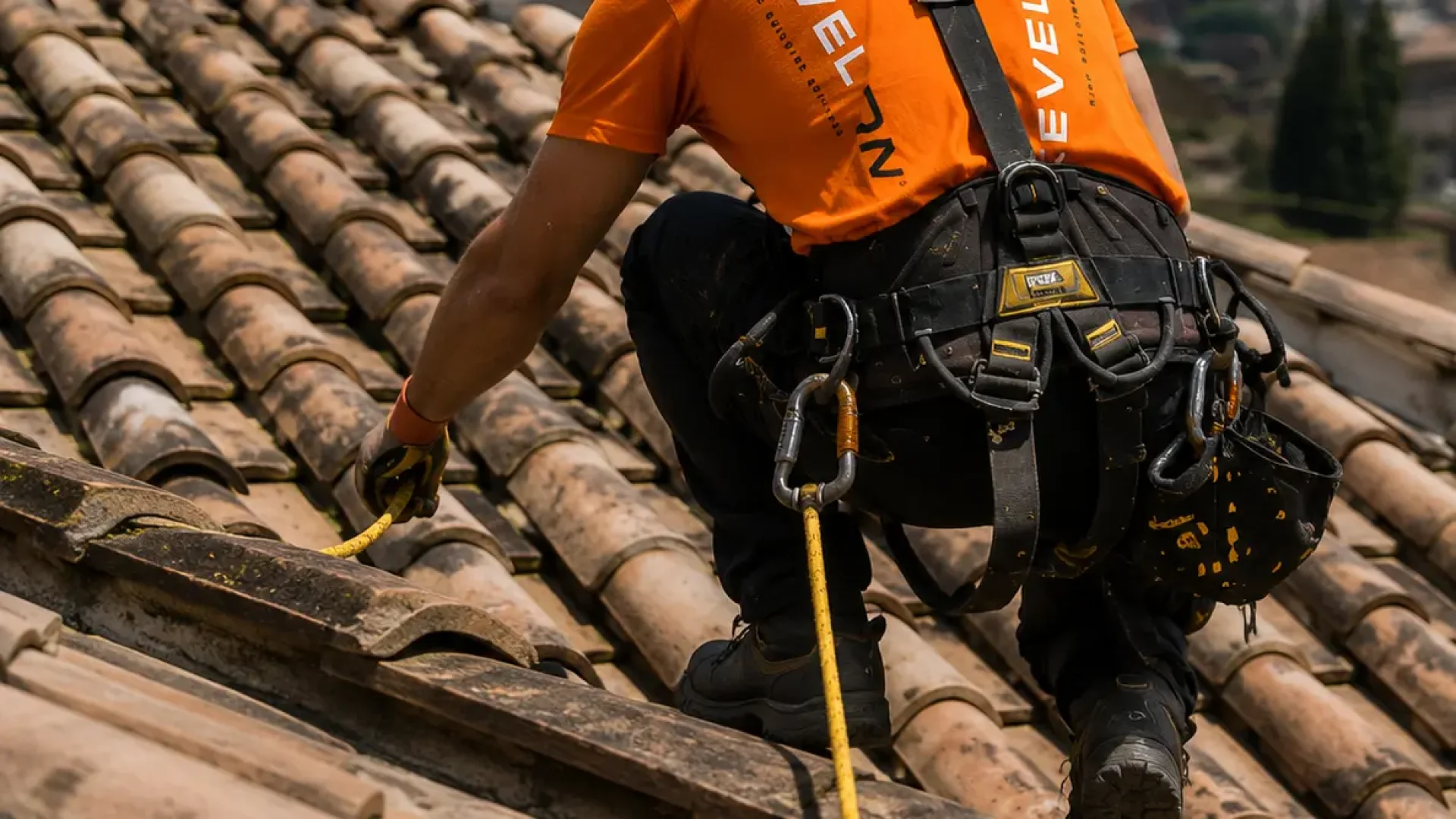 Técnico de Level On trabajando sobre una cubierta de tejas con arnés, cuerda de seguridad y equipo de protección.