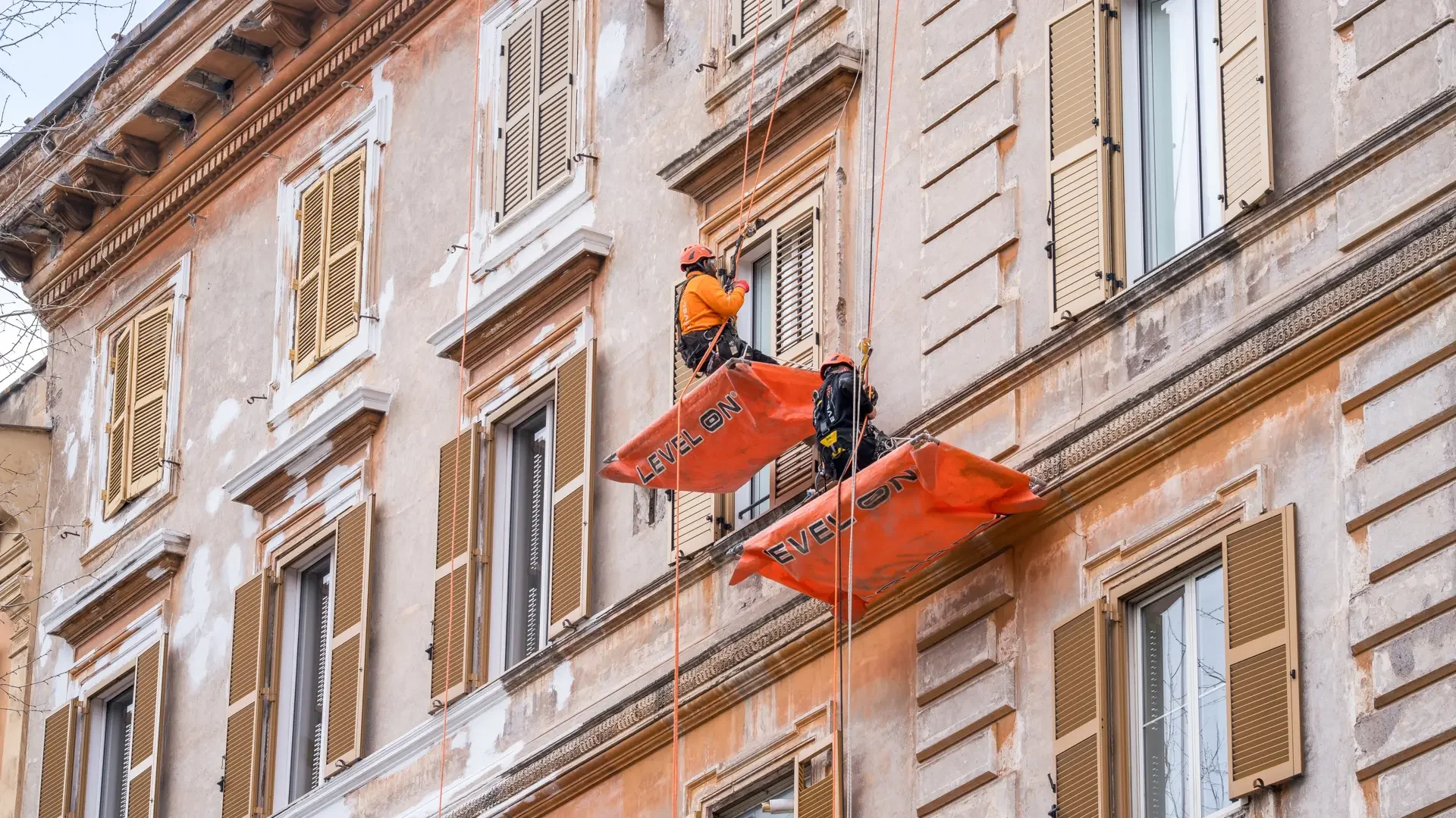 Dos técnicos de Level On realizan trabajos verticales en una fachada de Barcelona mediante sistemas de acceso por cuerda.